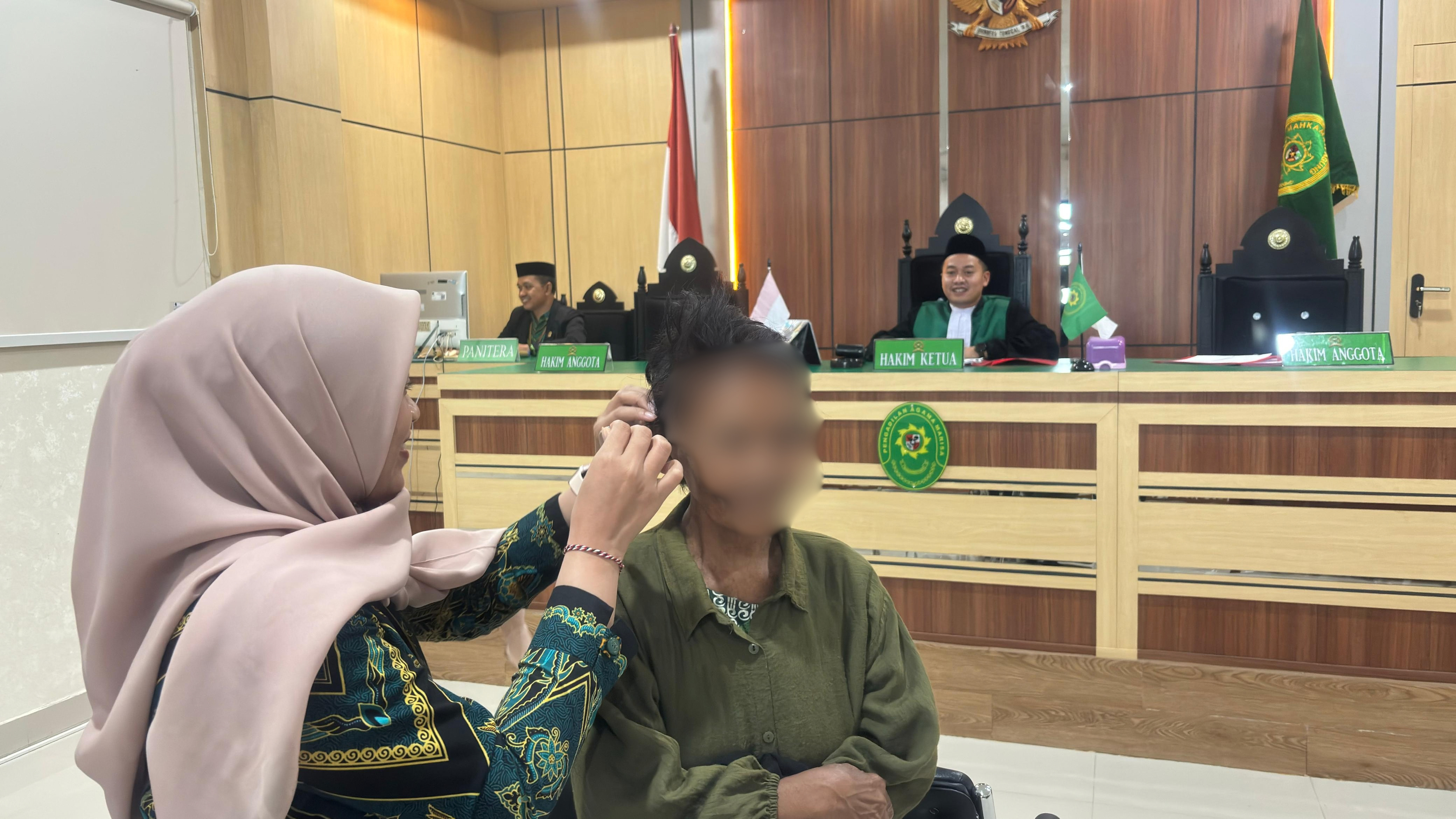 Petugas membantu memasangkan alat bantu dengar